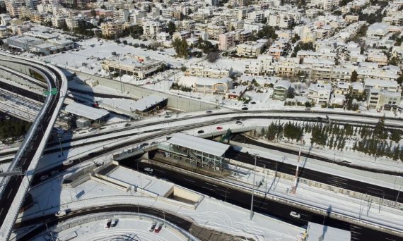 Aerial view of Athens city with snow-covered roads and buildings in winter.